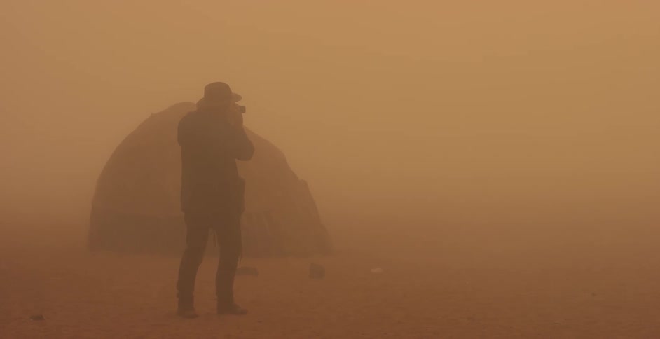 A man takes a photograph during a dust storm