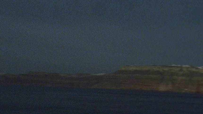Coastal cliffs are seen from a far shore