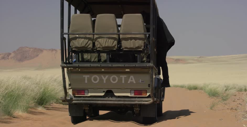 A man hikes towards his vehicle and enters