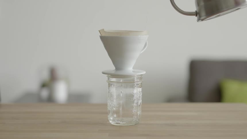 Water is poured through a filter and into a glass jar