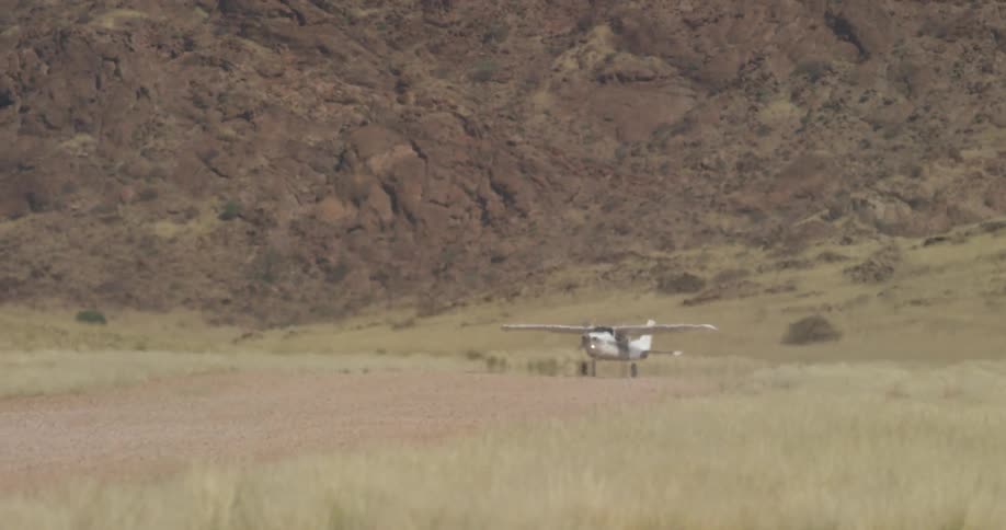 A small aircraft drives on an open field in a rural area