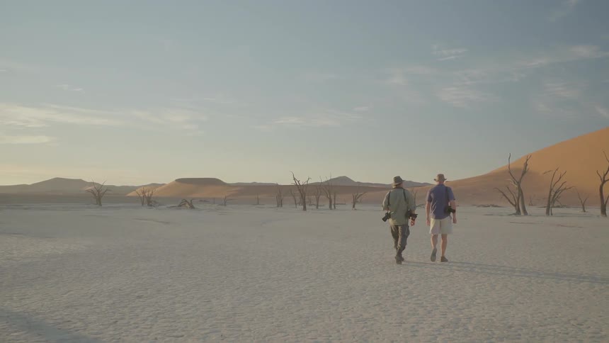 Two photographers walk in the desert
