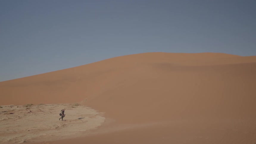 People walk a sand dune in the desert