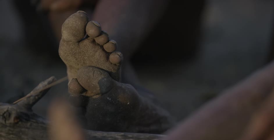 Sand covers the bottoms of a resting person's feet