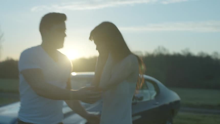 A woman in a slip fights with a man in a field at dawn