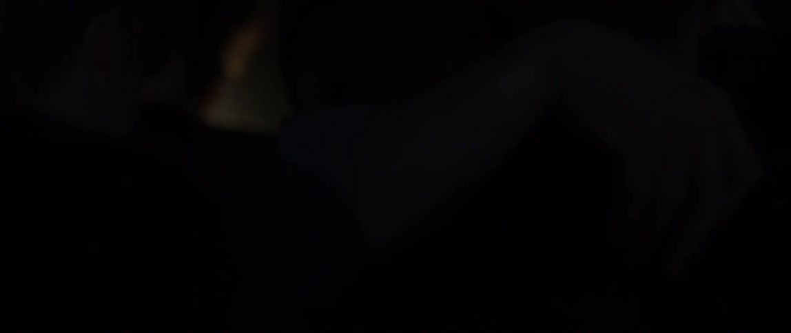 A man pushes his way through a crowd as lights flash