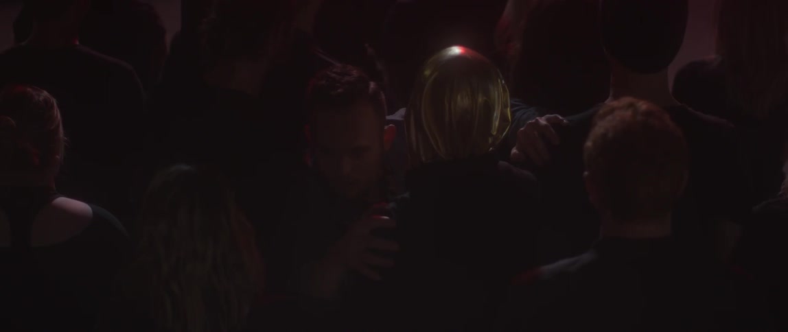 A person in a gold hood stands in the crowd