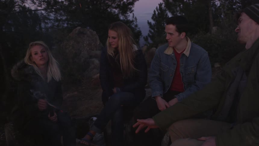 A group of friends sit around the campfire