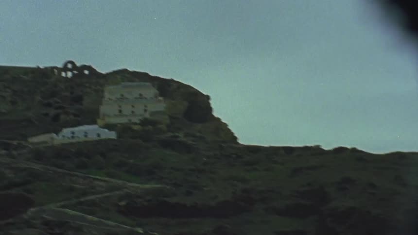 Buildings are on top of the tall mountain by the water