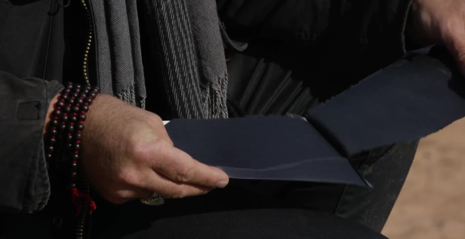 A man rips open an envelope with a photograph inside