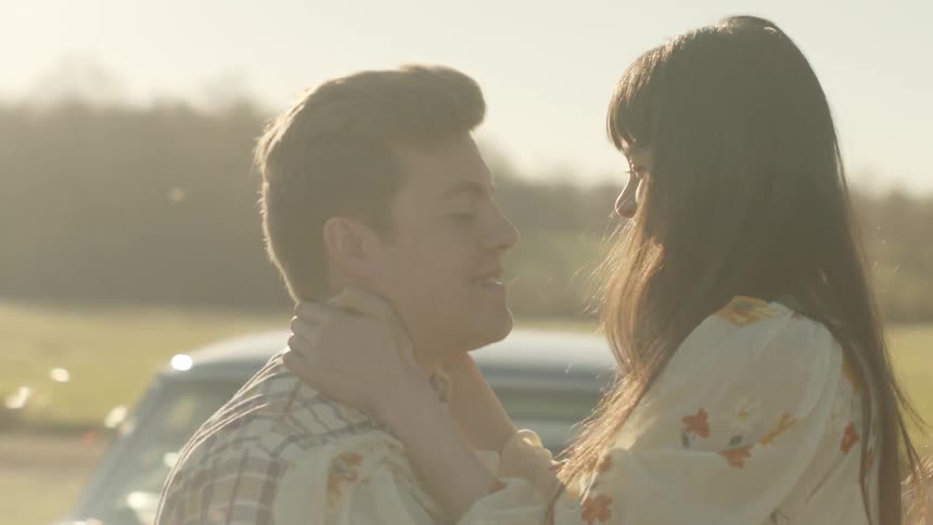 Man and woman hugging and kissing outside by car