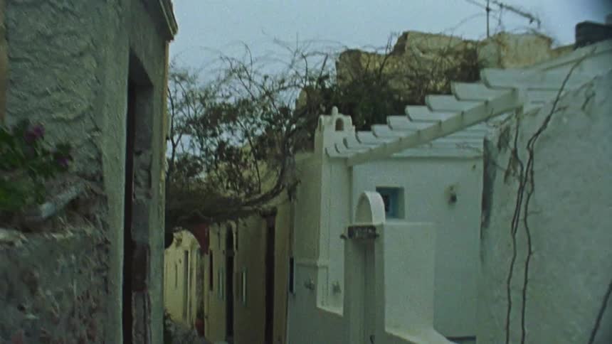 Someone is walking through an alleyway lined with mediterranean buildings