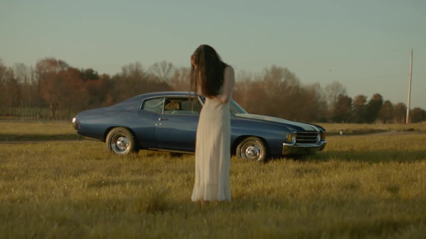 A woman holds her head in her hands out in a field