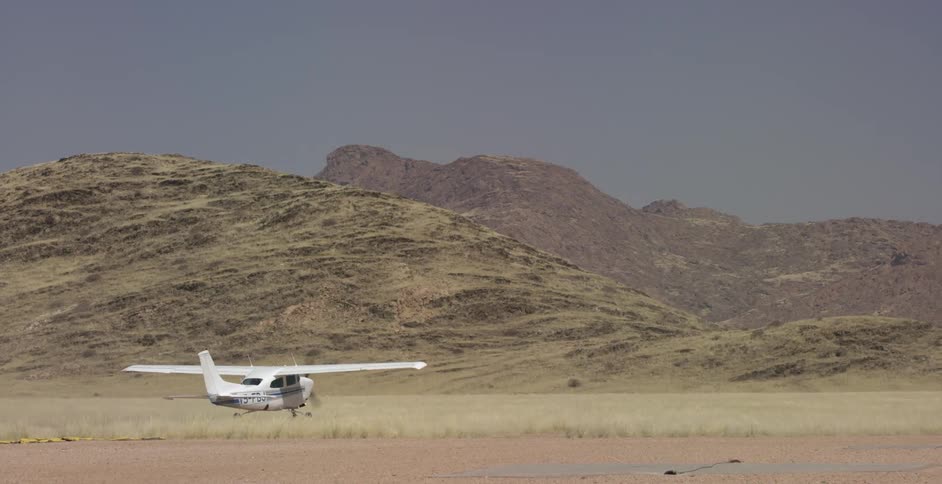 A small plane taxis down a dirt runway