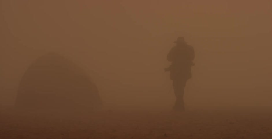 The silhouette of a man walking in a dust storm or haze