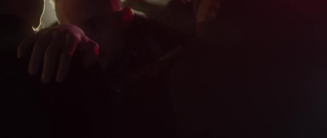 A man pushes past others in a dark club