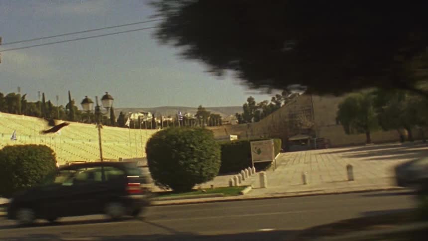 Vehicles travel down the street past a stadium