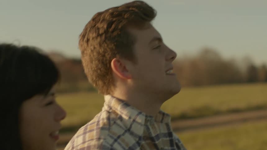 A man smiles and laughs as he sits talking with a woman