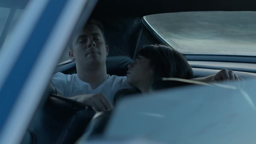 A man and woman sleep in the backseat of a car and the man jolts awake