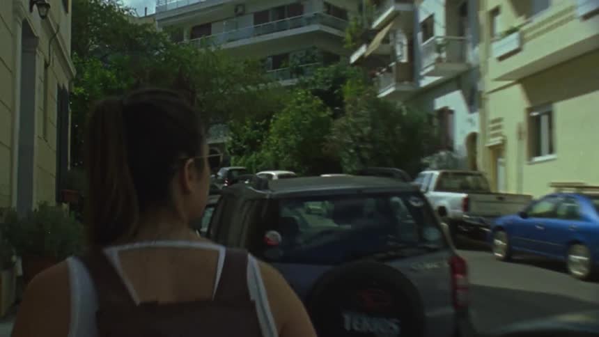 A woman walks down the sidewalk looking around