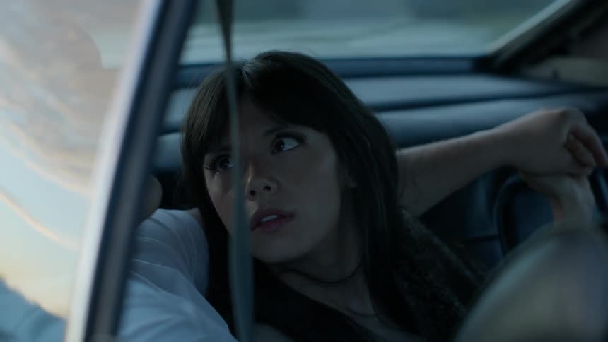 A woman and man lay and embrace in the back of a car
