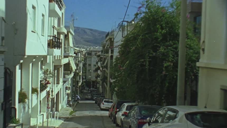 A vehicle turns a corner and travels down a narrow urban street