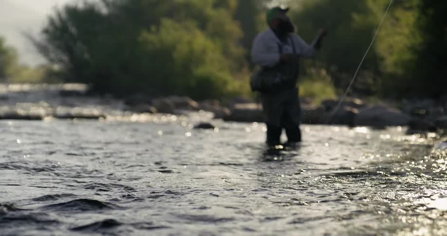 A fisherman is casting his line into a river