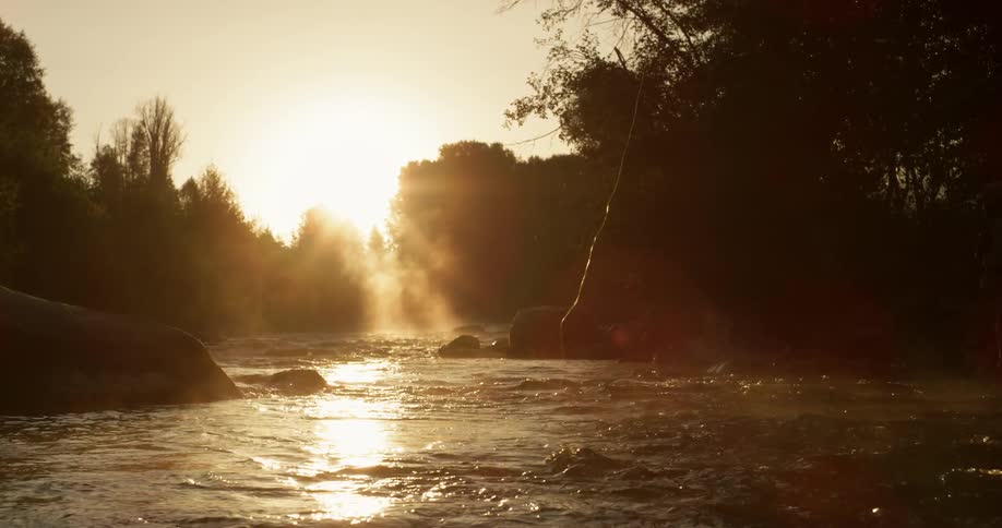 A fishing line plays out over a river at dusk or dawn