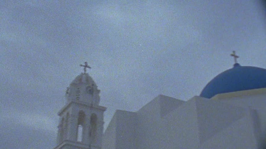 A cross sits on top of a church tower on a cloudy day