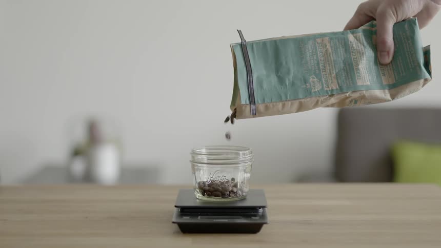 A person is dropping coffee beans into a container