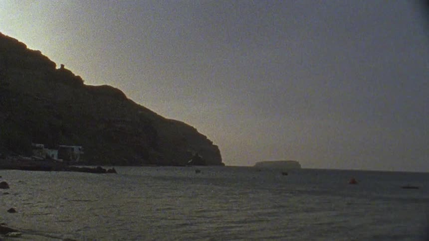 The water crashes against the shore at sunset