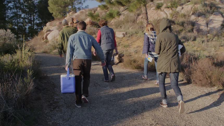 Group of people holding wood and coolers walking down a path