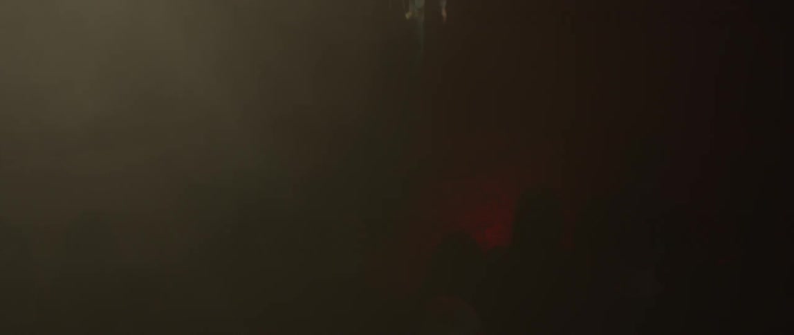 Colored lights flash as a man walks toward a crowd of people