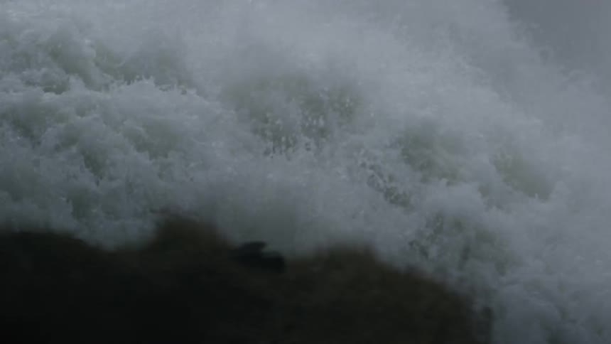 Water from the waterfall coming down with a great force and crashing the bottom