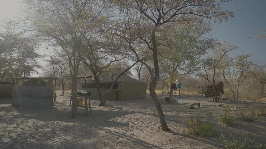 A man is walking in an african village in late afternoon
