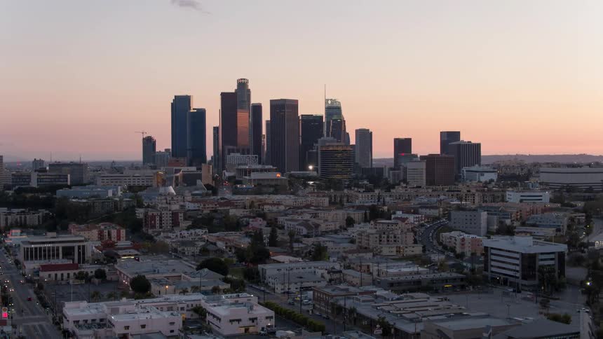 The sun sets behind a cityscape with skyscrapers