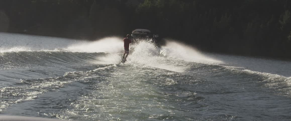 A person is cruising along the sea waters by holding a rope attached to a jet boat