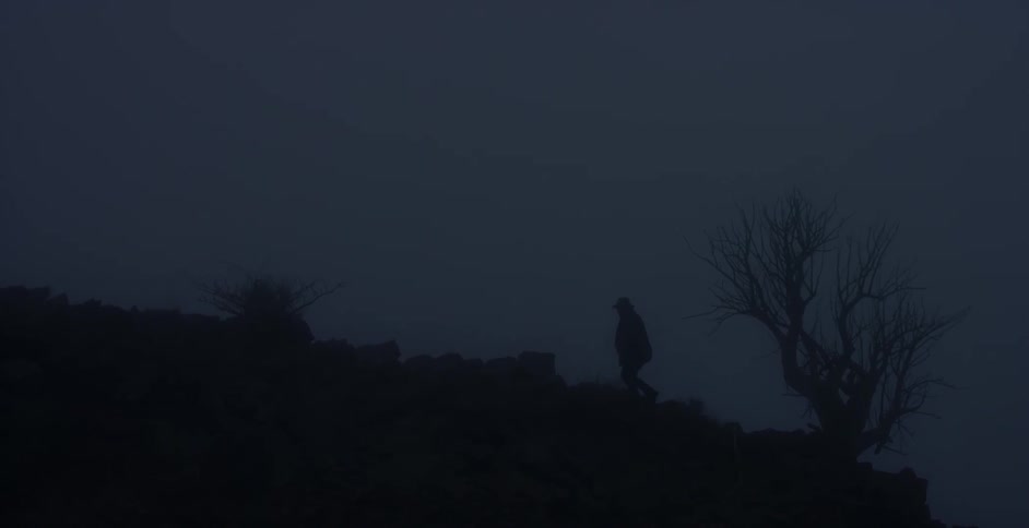 A man is walking along a ridge line at night