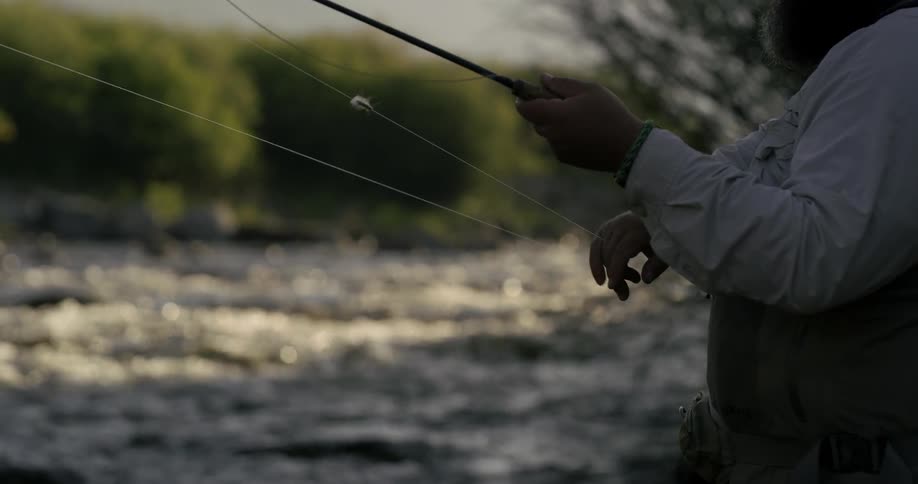 A fisherman is adjusting his line and reel as he is fishing