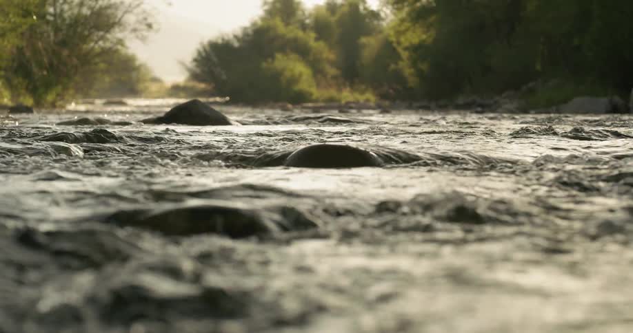 The water flows over the rocks in the stream at sunset