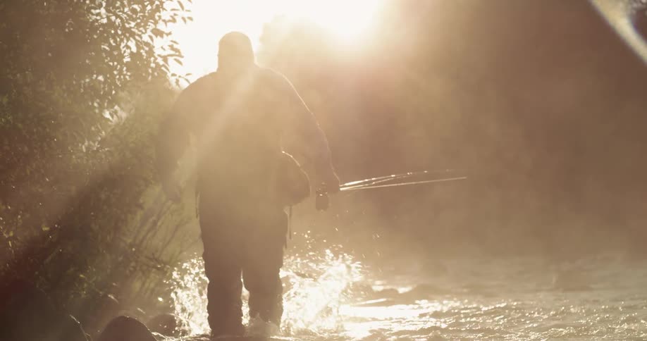 A fisherman is walking in a rocky stream