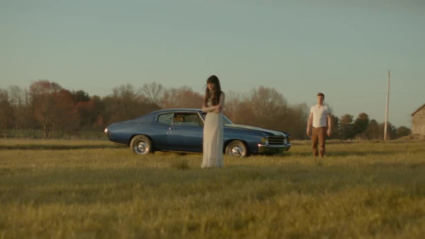 A man walks toward a woman standing in the grass and stops