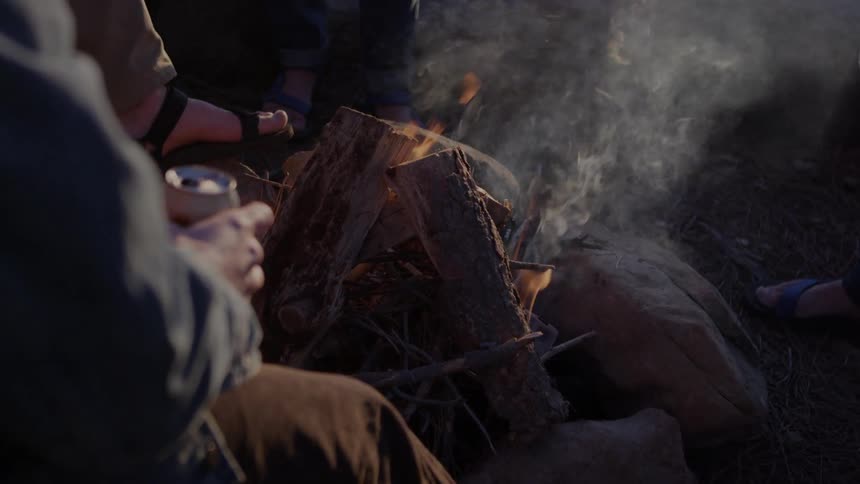 Man sitting in front of a fire with beer