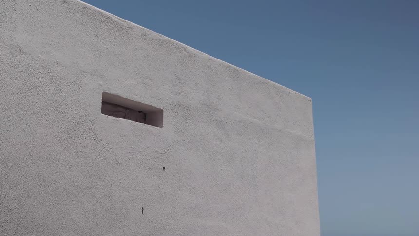 A stucco building stands out against a blue sky