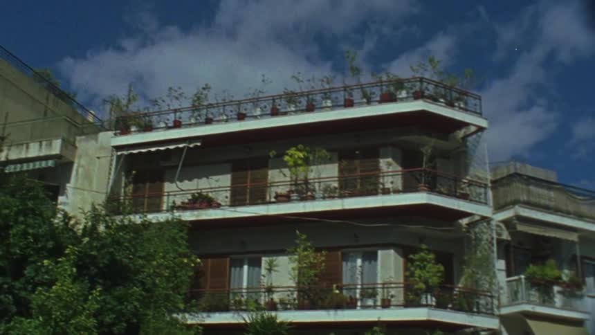 The building is tall with plants on the roof