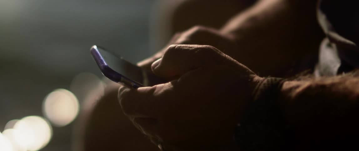 A man types on his phone next to the water