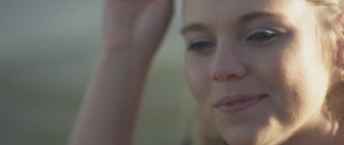 A blond woman puts on sunglasses