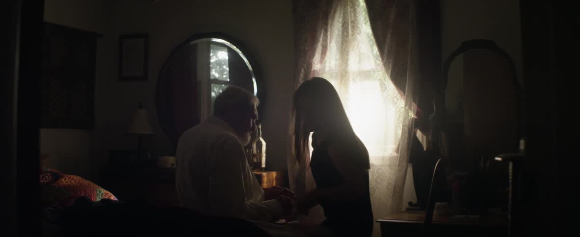 A woman helps an elderly man sit down