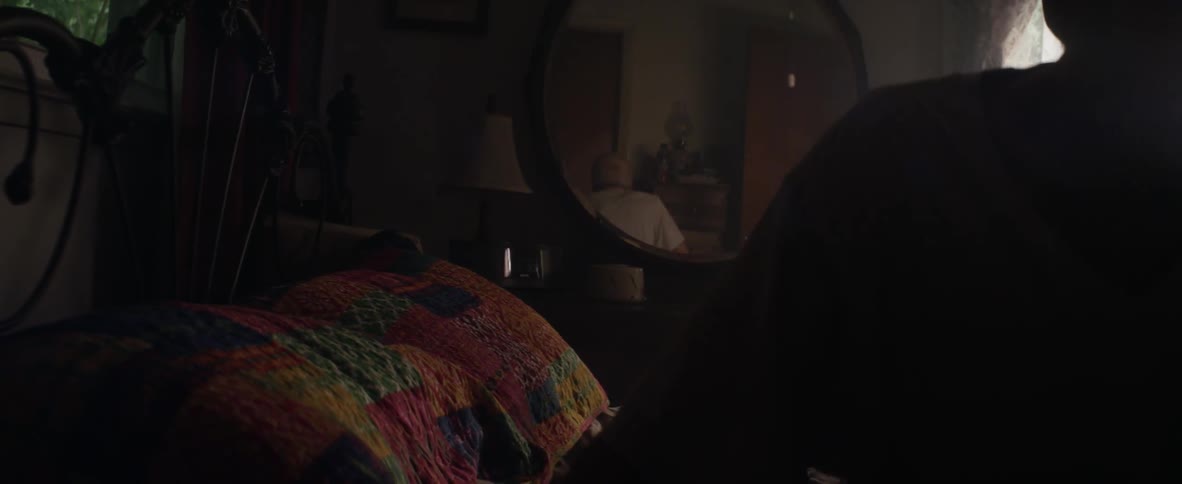 An elderly man leans up to get out of bed