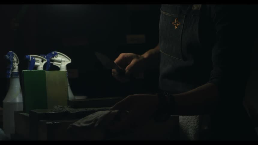 A man is sharpening a knife and wiping it off